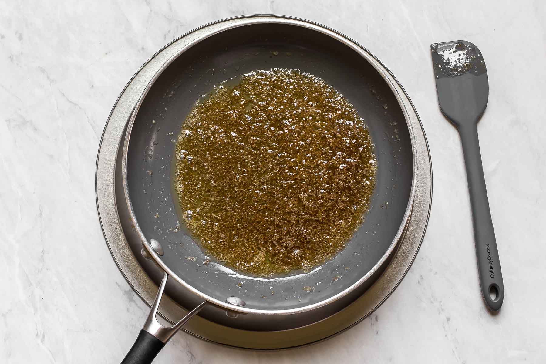 Melted butter and brown sugar in a skillet with a spatula.