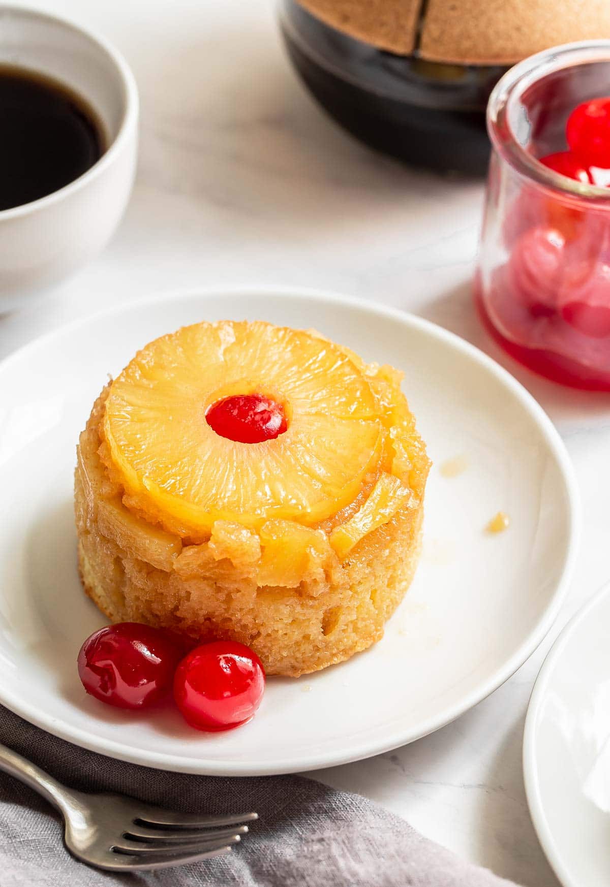 Pineapple cake on plate with red cherries.