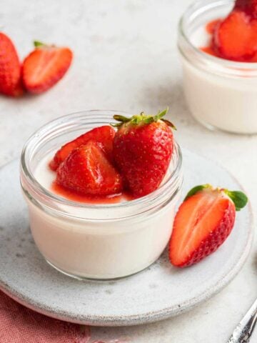 Close up shot of panna cotta recipe for two with strawberries on top.