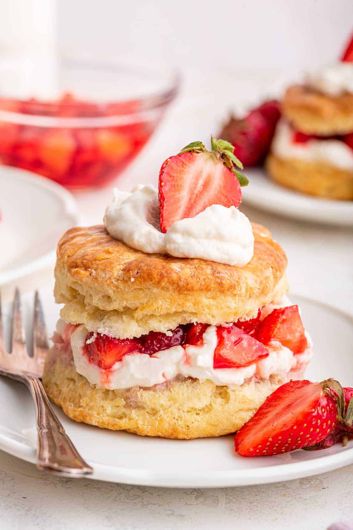 Close up image of strawberry shortcake with whipped cream and strawberry on top.