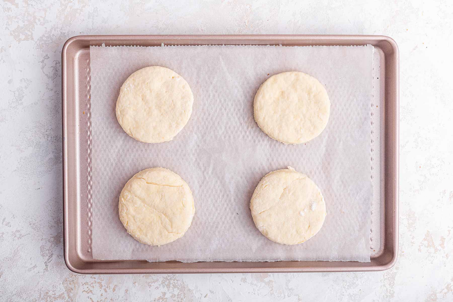 Four biscuits on mini sheet pan, pre-baking.