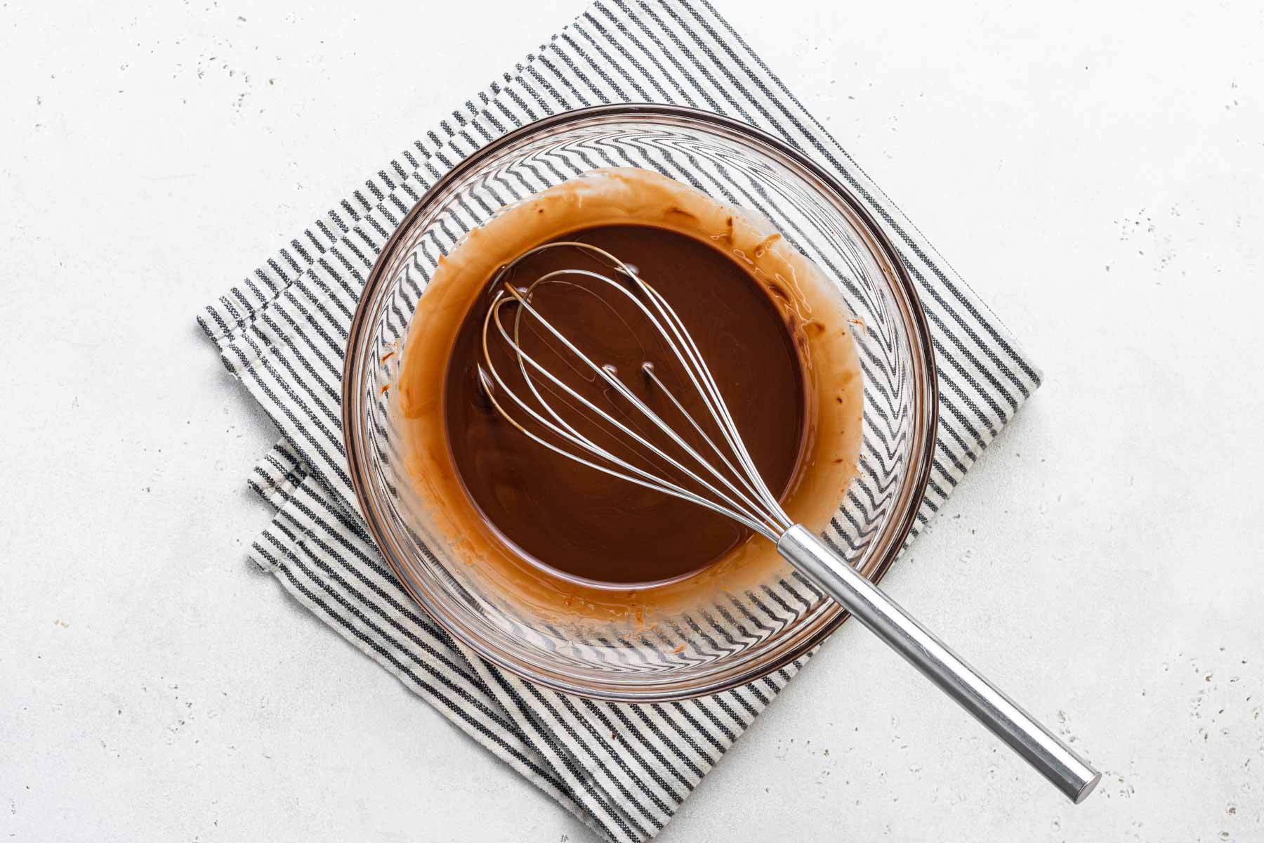 Melted chocolate in bowl with whisk.
