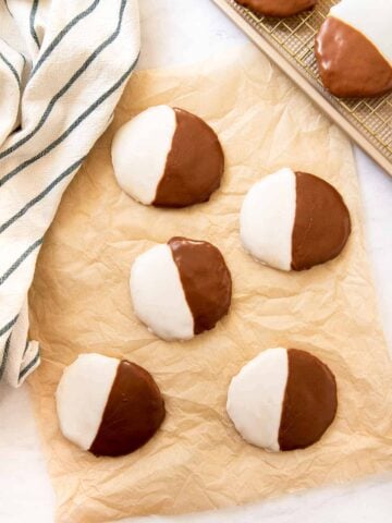 Five black and white striped cookies on parchment paper.