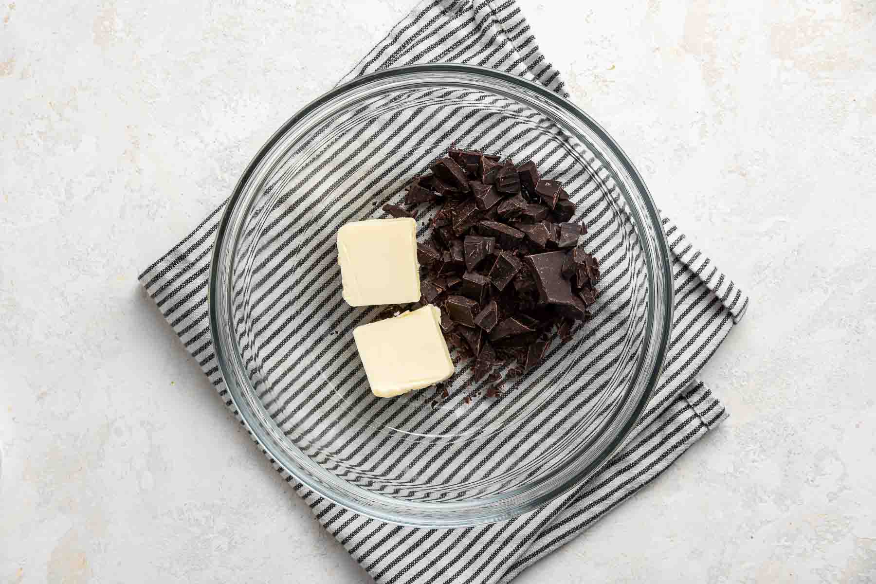 Chopped semisweet chocolate and butter in a clear glass bowl.