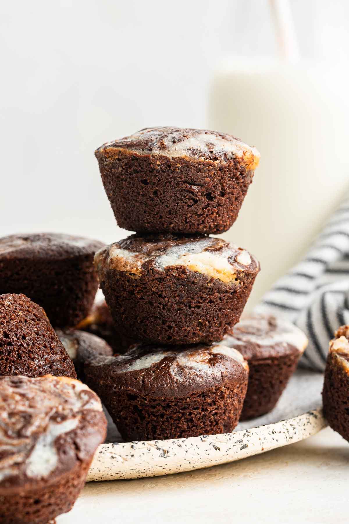 Three cheesecake brownie bites stacked on top of each other.