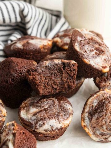 Cheesecake brownie bites piled up with one cut in half to show fudginess inside.
