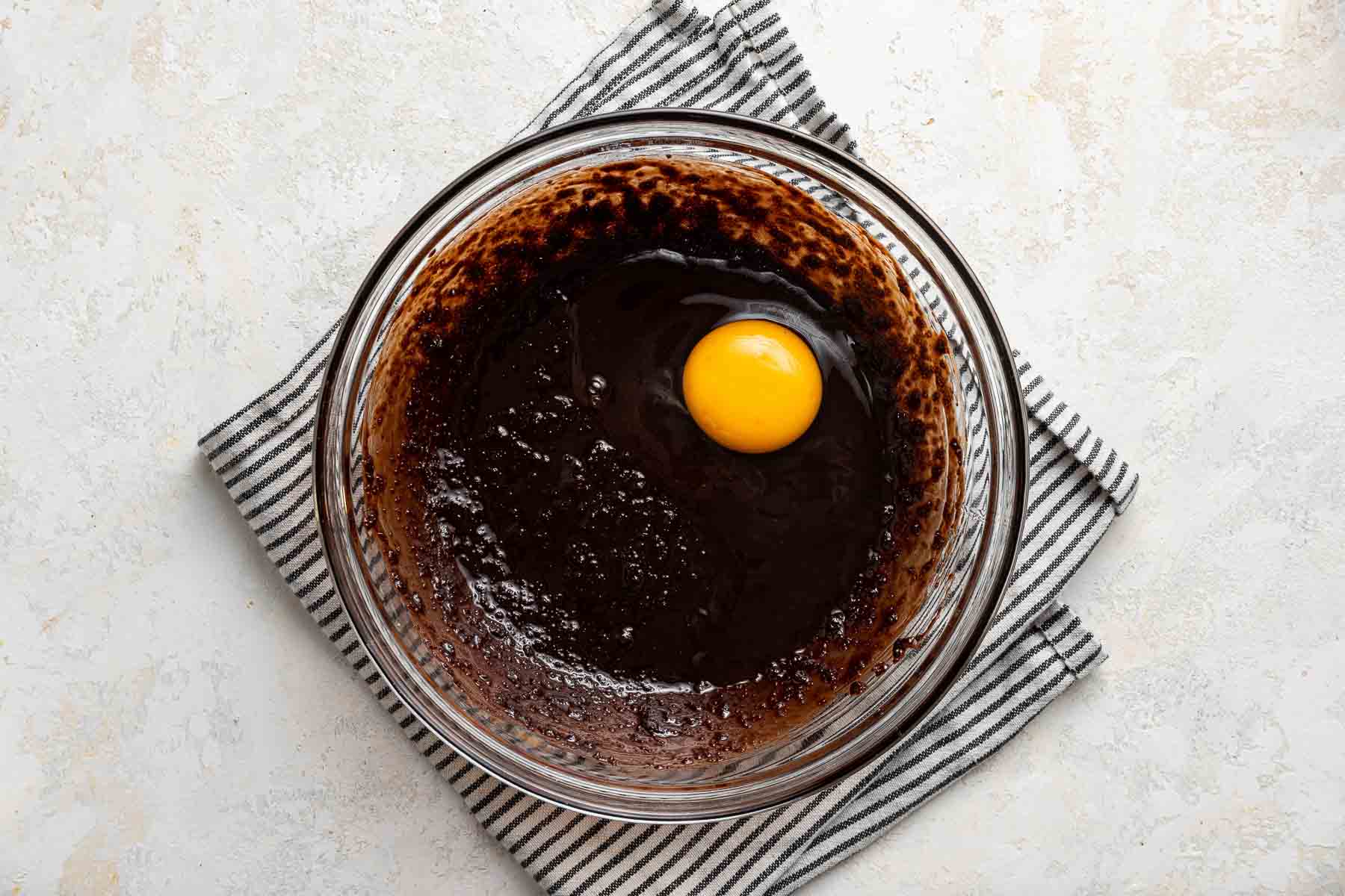 Adding a raw egg to brownie batter.