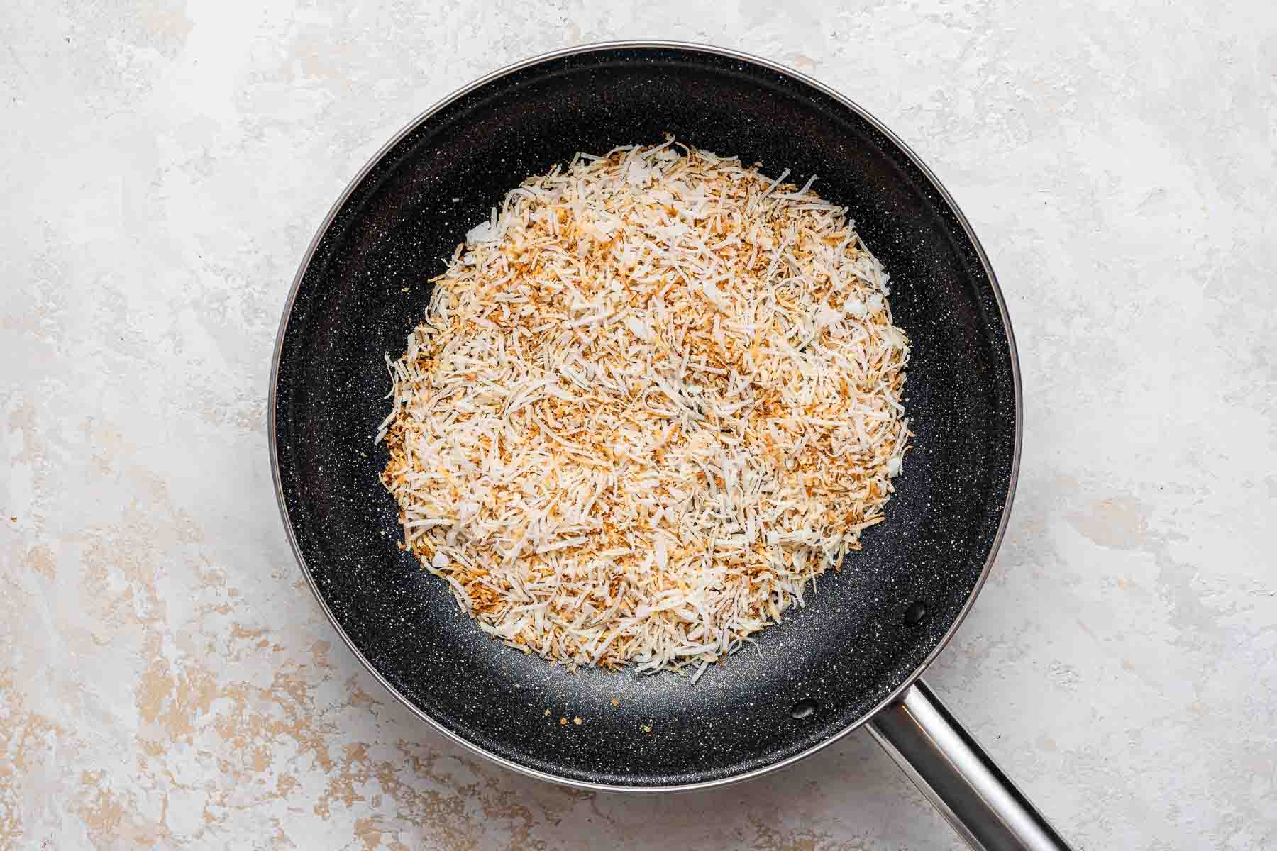 Toasting coconut flakes in a skillet.
