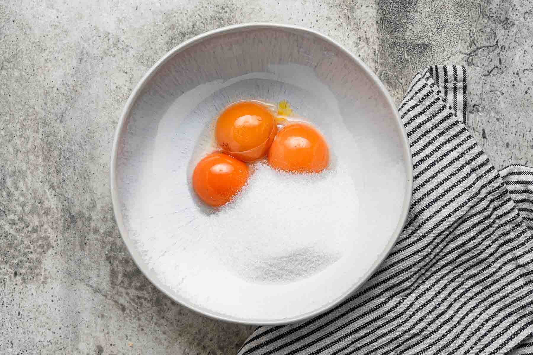 Egg yolks and sugar in shallow bowl.