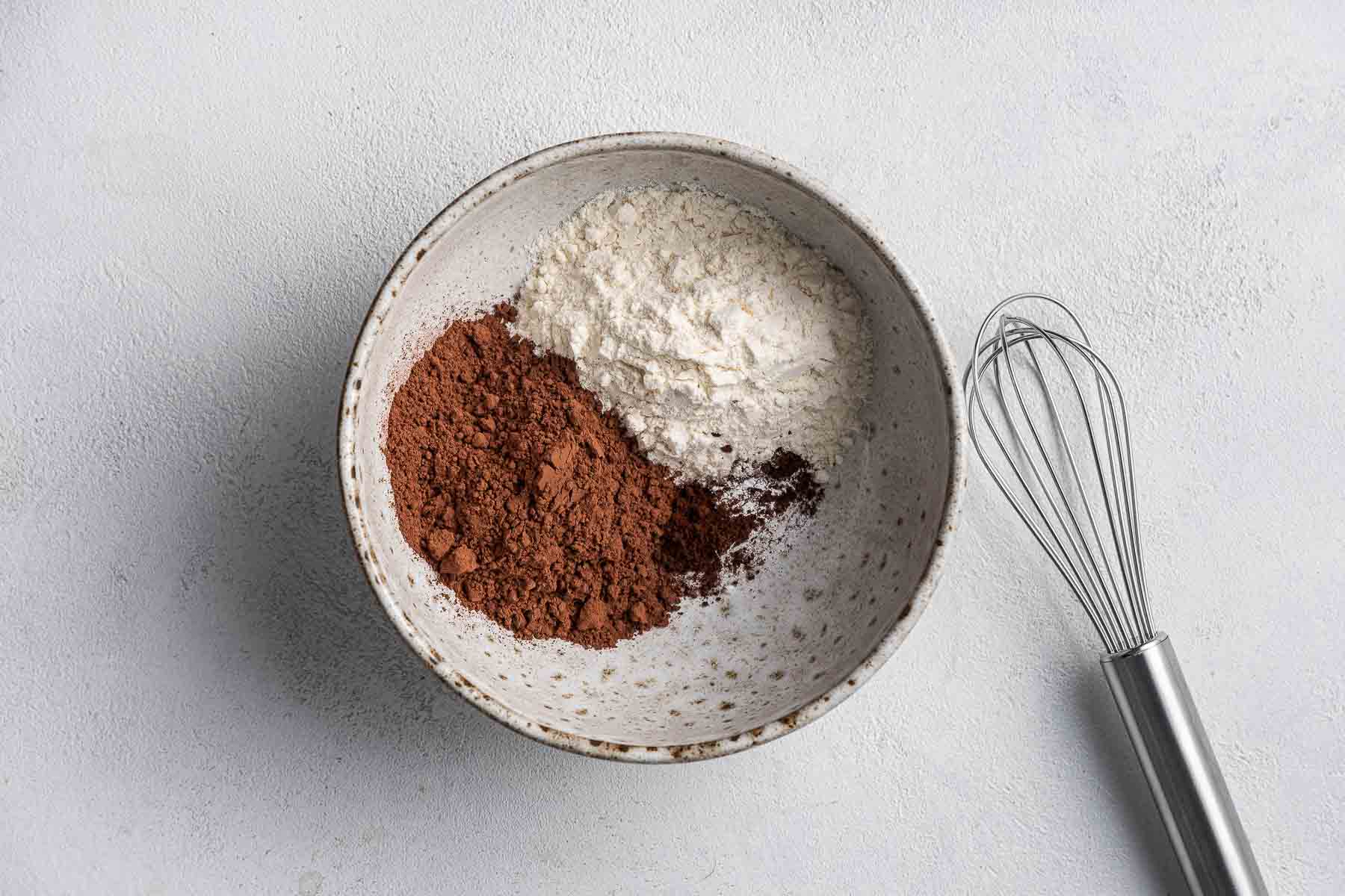 Whisking flour and cocoa powder together in a small bowl.