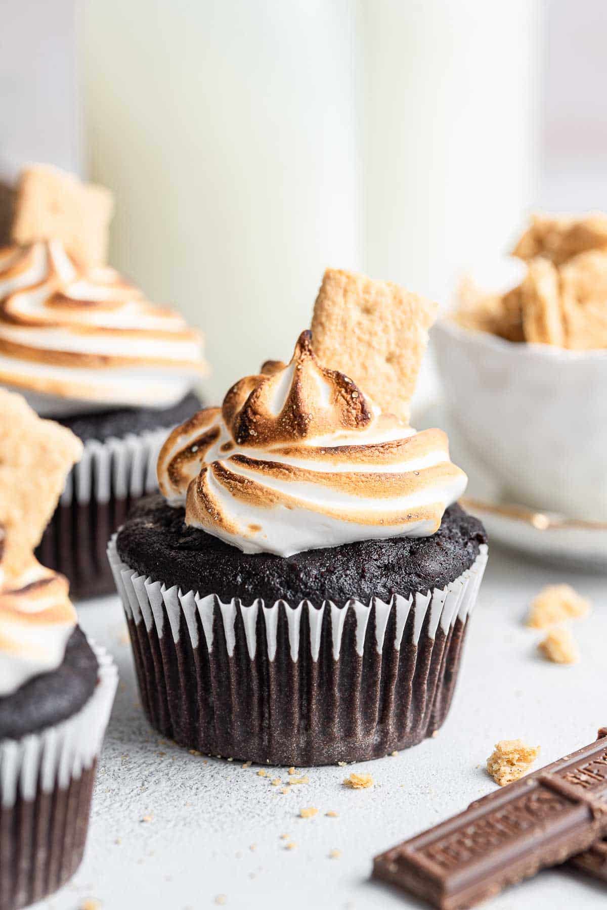 Chocolate cupcake with torched white frosting and graham cracker piece.