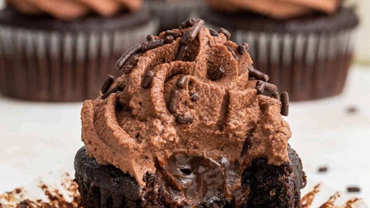 Close up shot of chocolate cupcake cut in half with chocolate center and swirled chocolate frosting.