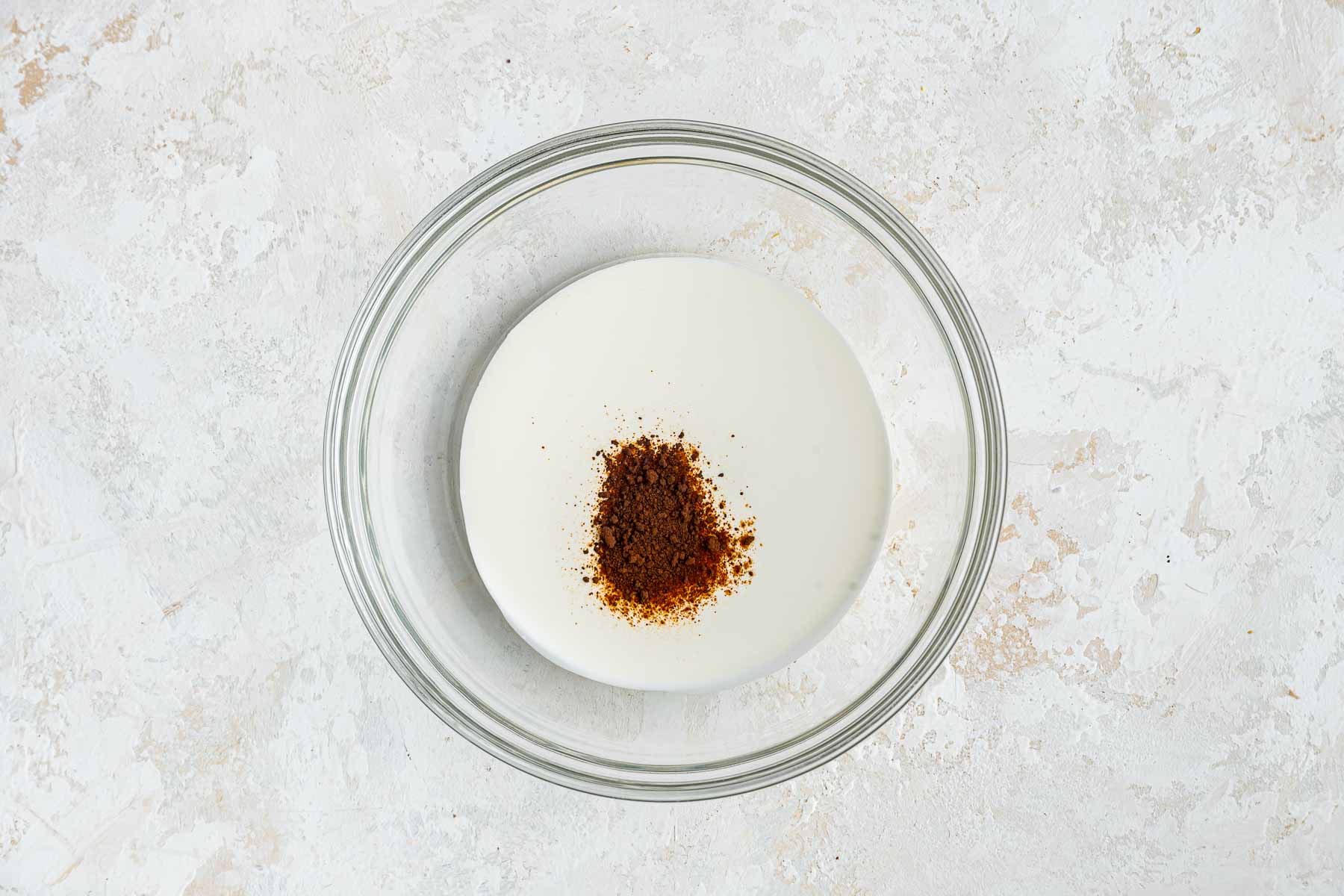 Heavy whipping cream in bowl with espresso powder on top.