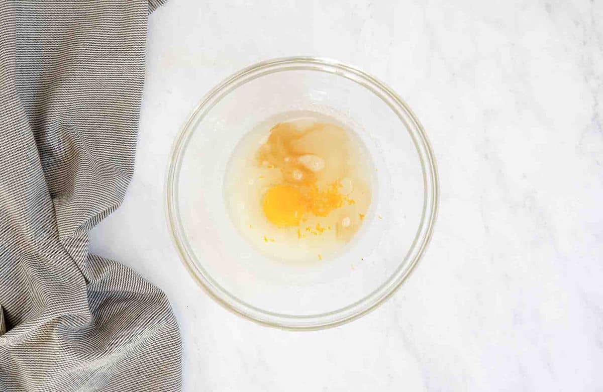 Clear bowl with cupcake ingredients and egg.