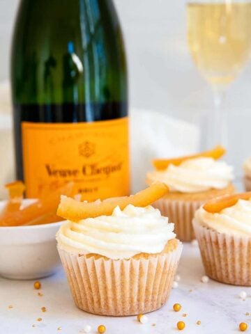 White cupcakes with champagne bottle in background.