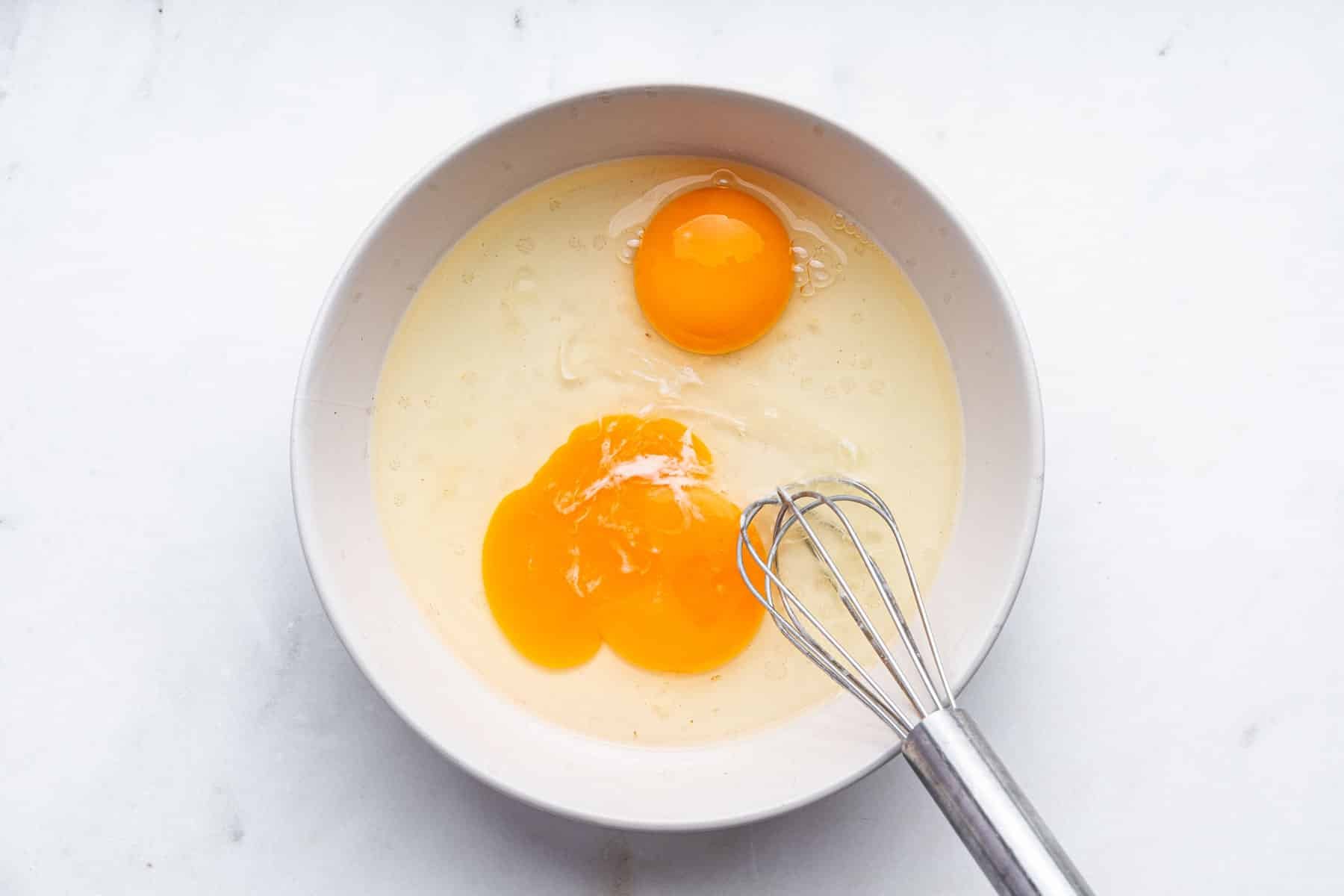 Yellow liquid in bowl with two eggs added.