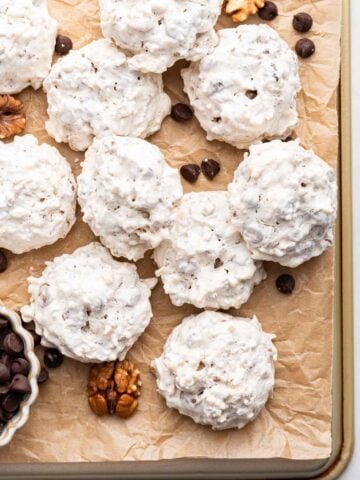 Forgotten meringue cookies on a baking sheet with pecans and chocolate chips.