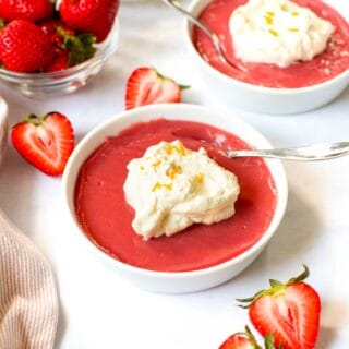 Two bowls of strawberry pudding with whipped cream on top.
