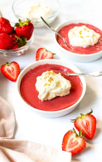 Two bowls of strawberry pudding with whipped cream on top.