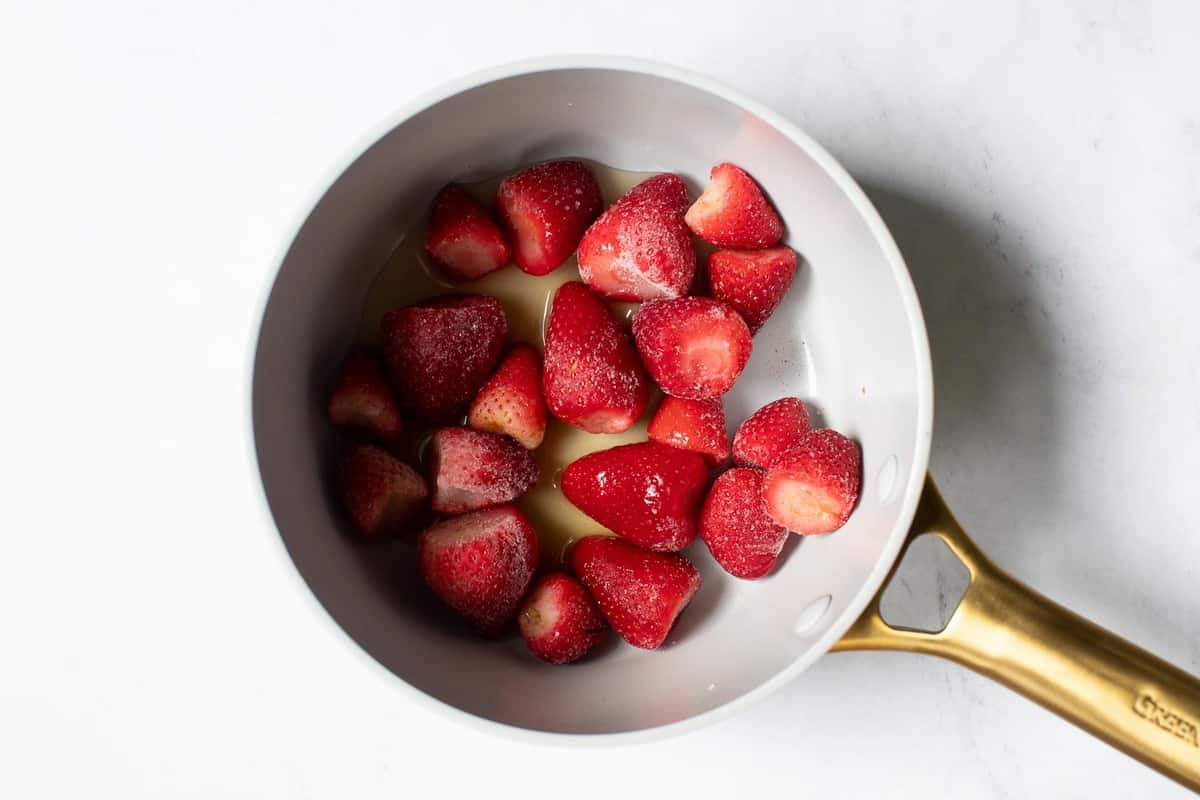 Whole strawberries in pan with sugar.