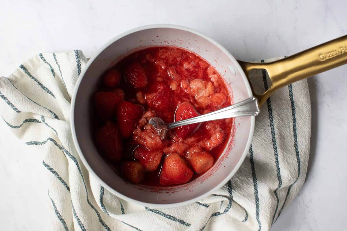 Cooked strawberries in shallow pot.