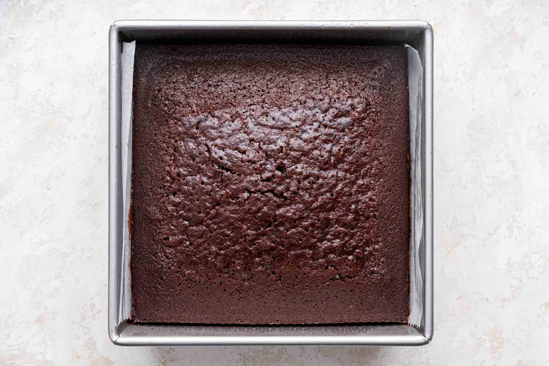 Freshly baked chocolate cake in a square pan.