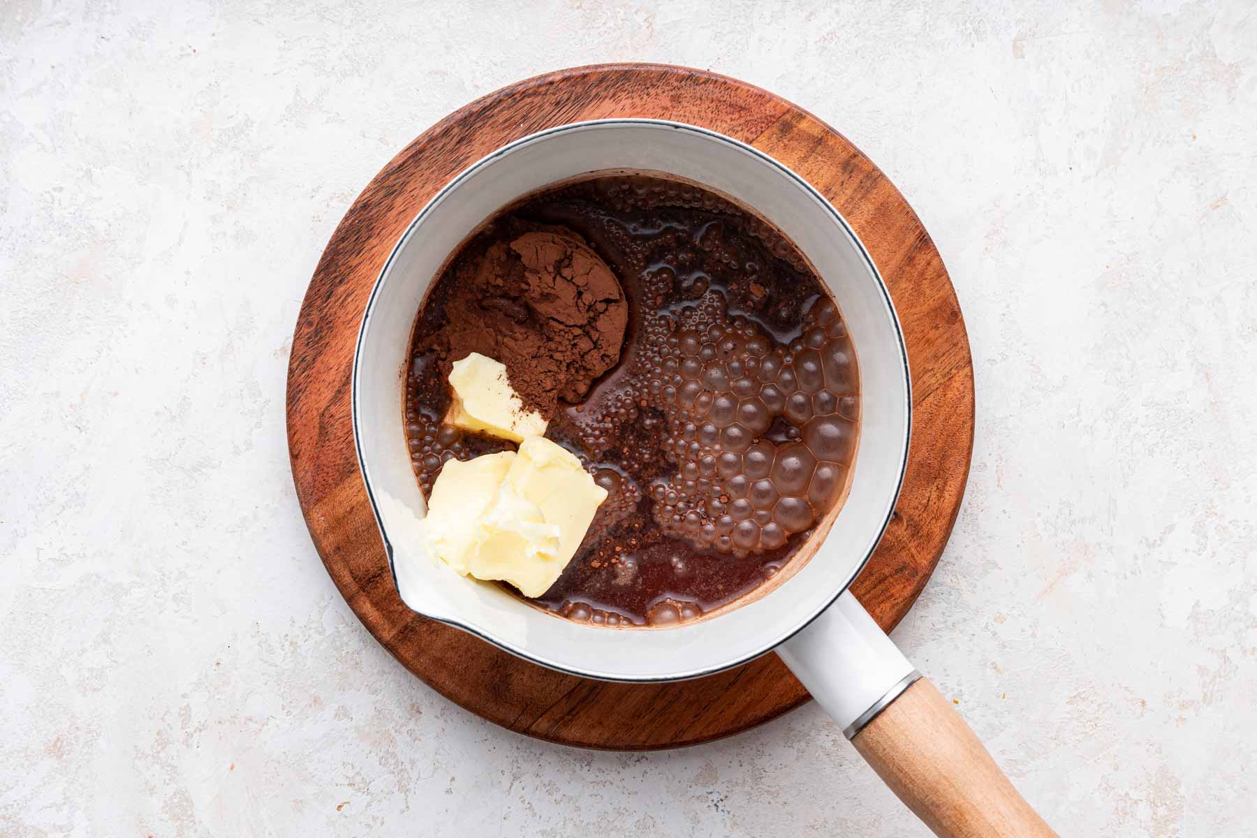 Small white saucepan with cocoa, soda and butter.