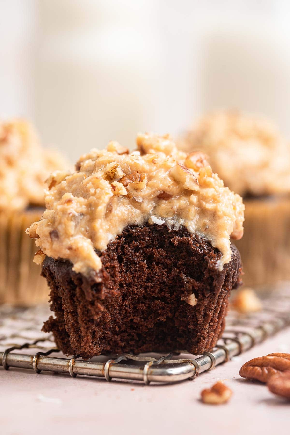 Single chocolate cupcake with creamy brown frosting with pecans.