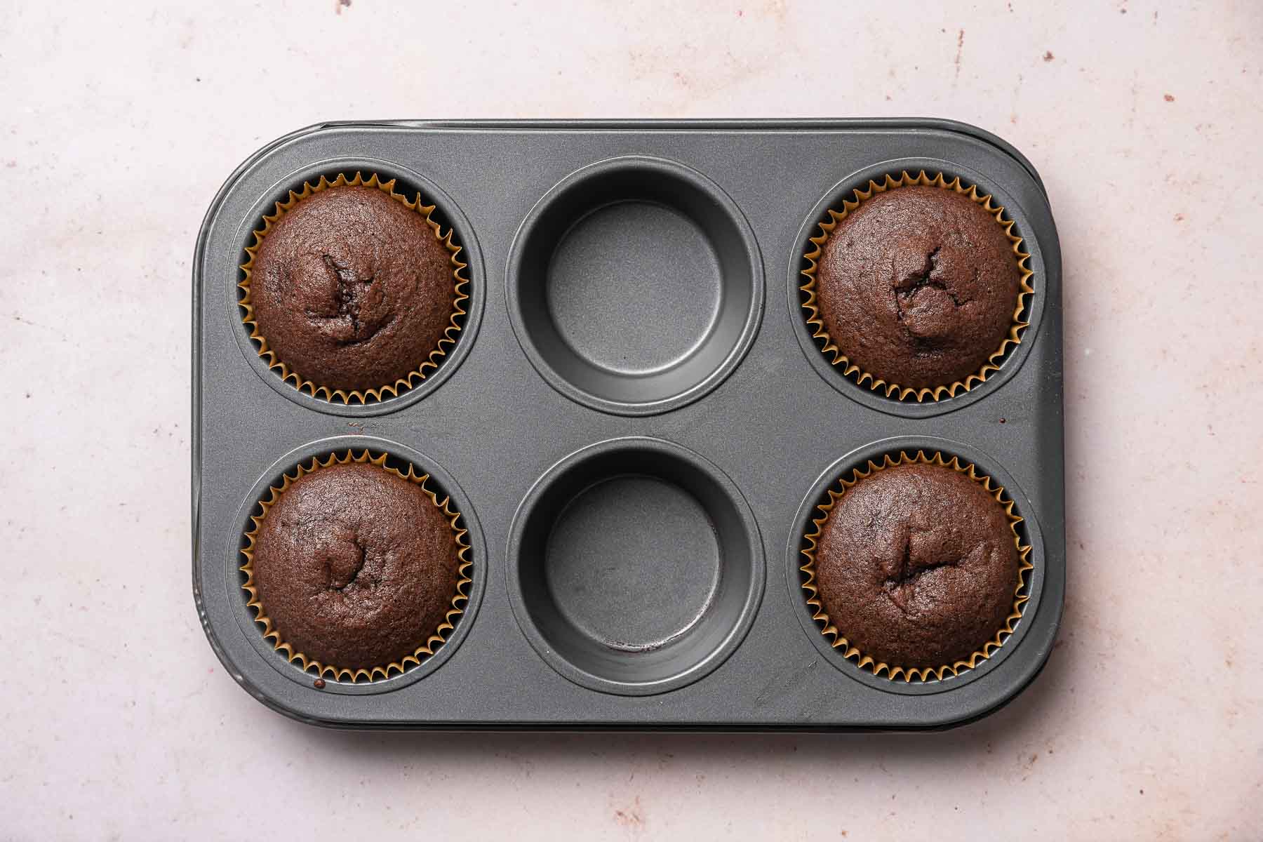 Four chocolate cupcakes in a 6 cup pan.