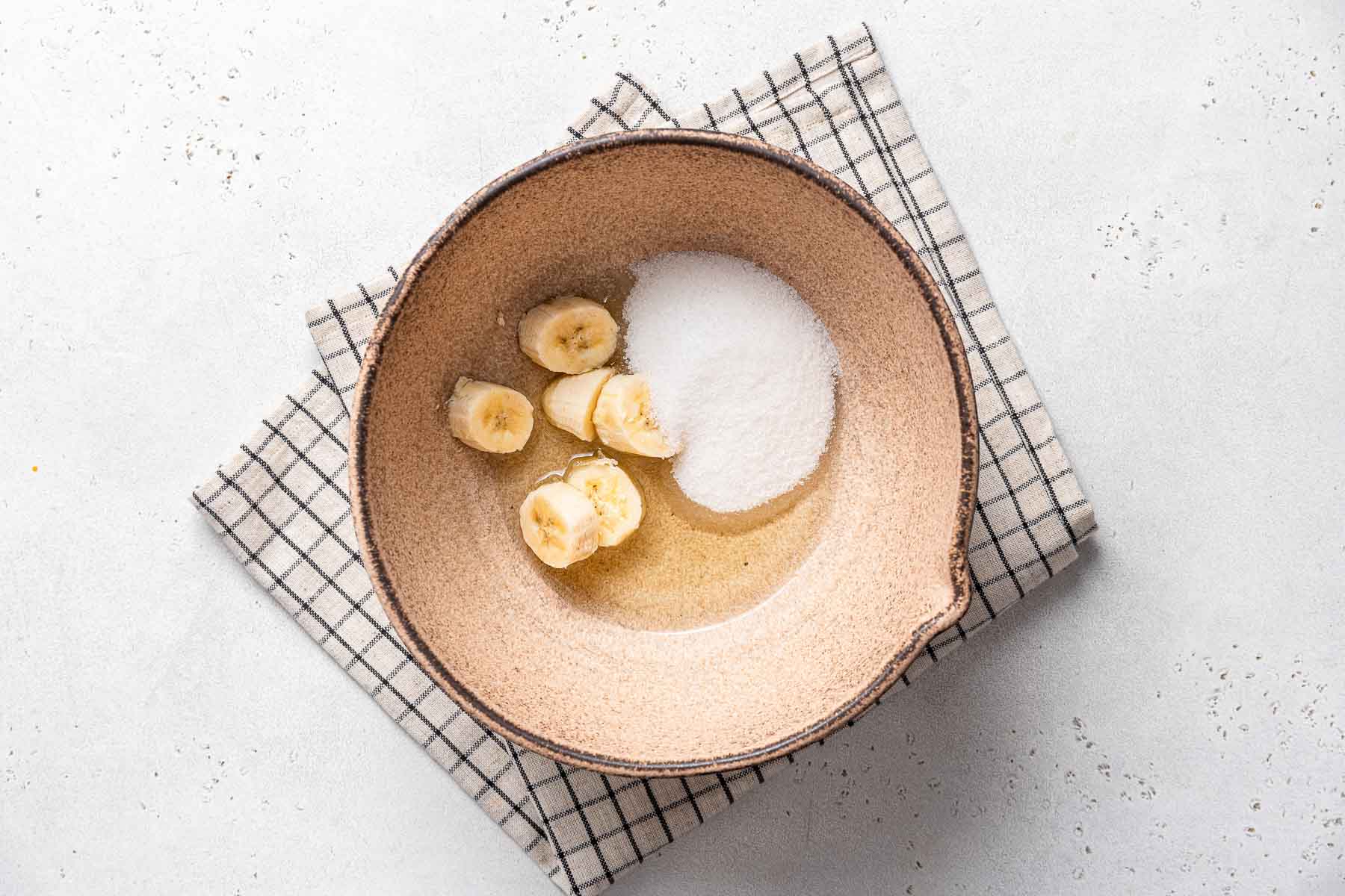 Banana, oil and sugar in light brown bowl.