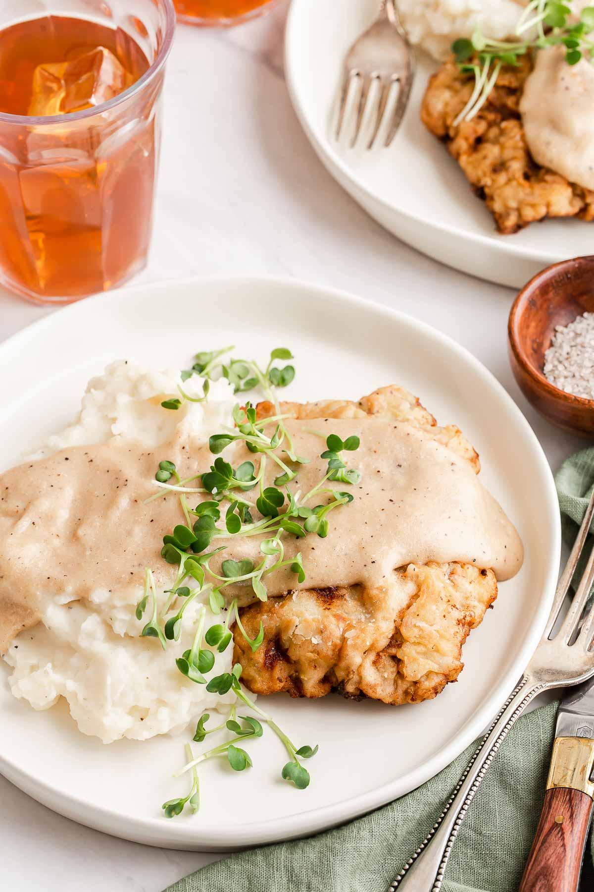 Plated chicken fried steak with mashed potatoes and gravy.