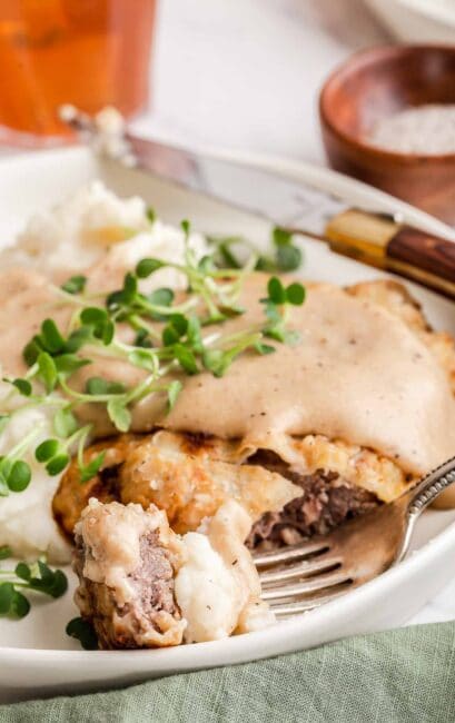 Chicken fried steak on a plate with a bite cut out.