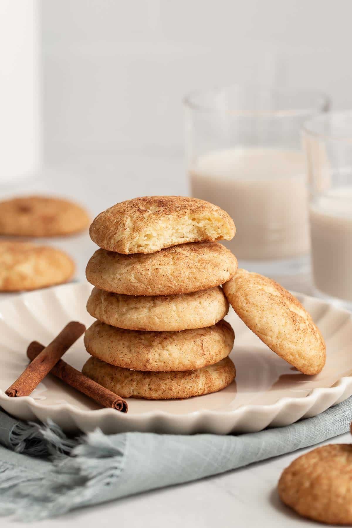 Stack of snickerdoodles on plate with top cookie missing a bite.