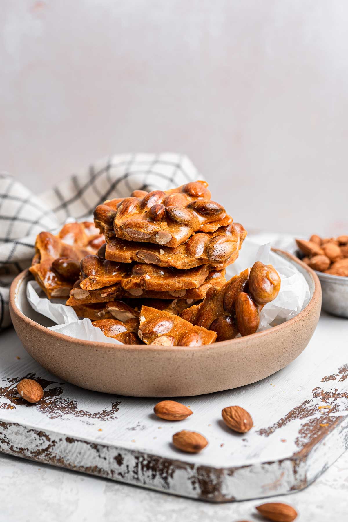 Almond brittle stacked in bowl.