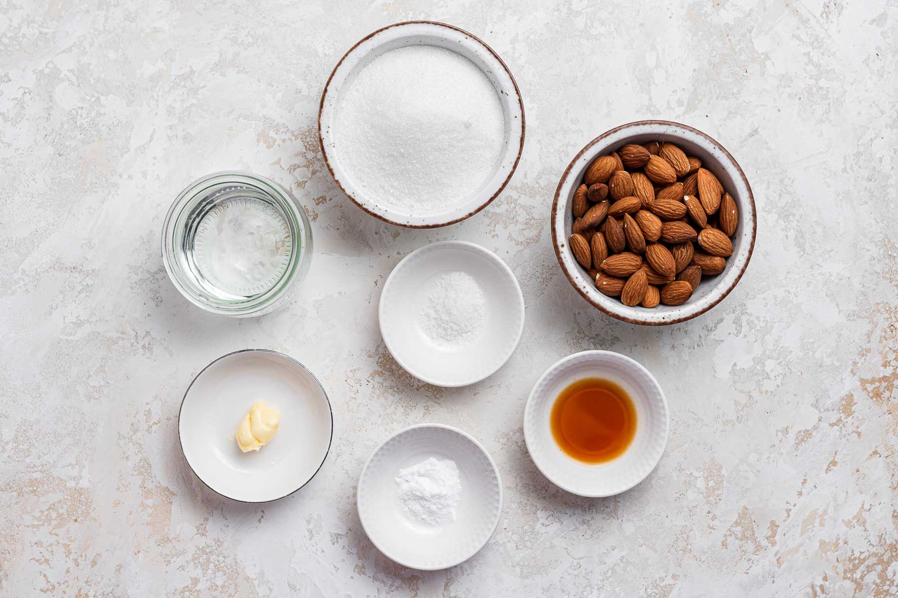 Ingredients for almond brittle on white table.