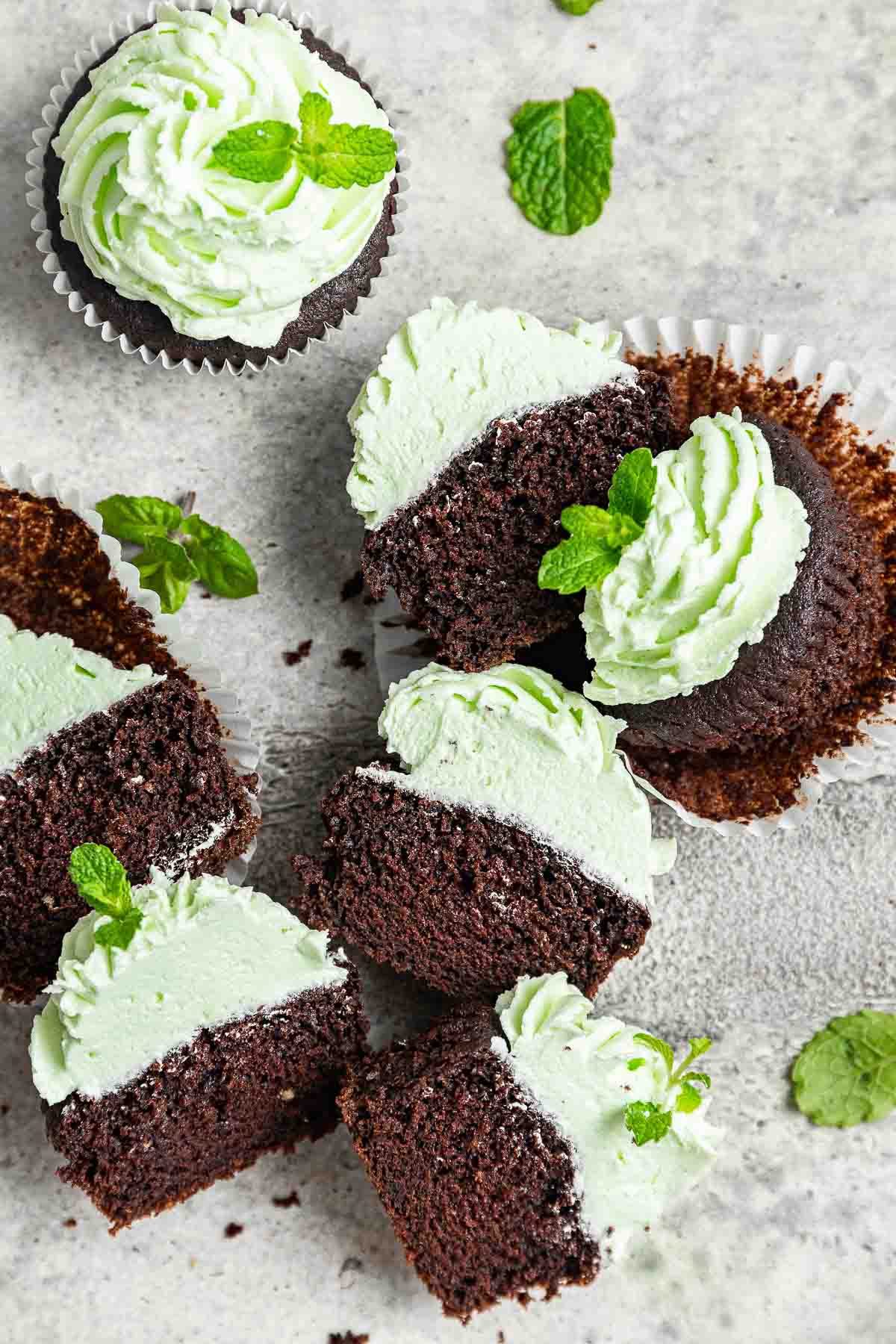 Cut open chocolate mint cupcakes with pale green buttercream.