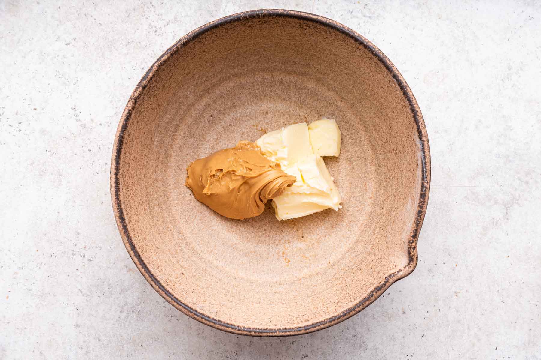 Peanut butter and softened butter in a brown mixing bowl.