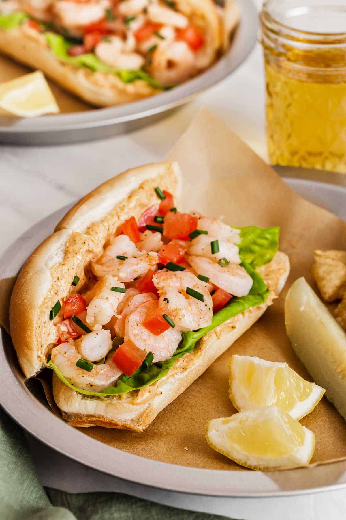 Fresh shrimp sandwiches served with lemon wedges and a pickle.