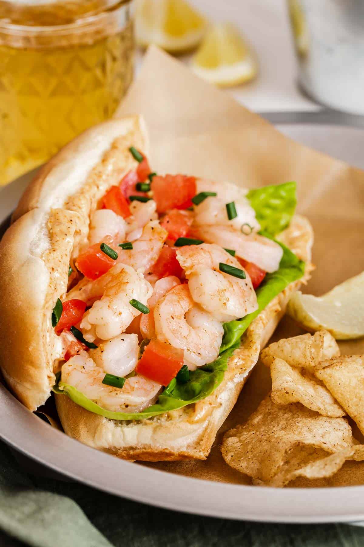 Shrimp po boy sandwich with tomatoes and lettuce on a roll.