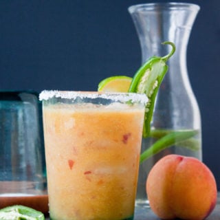 Peach margarita with jalapeno in glass.