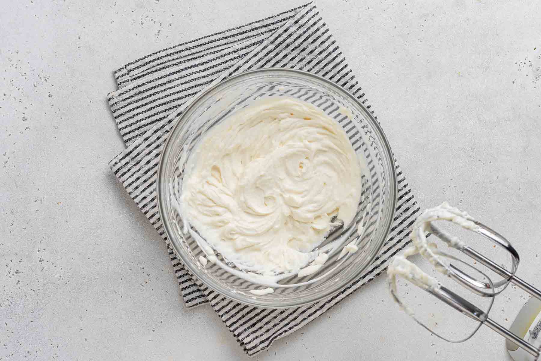 Freshly whipped cream in bowl with mixer.