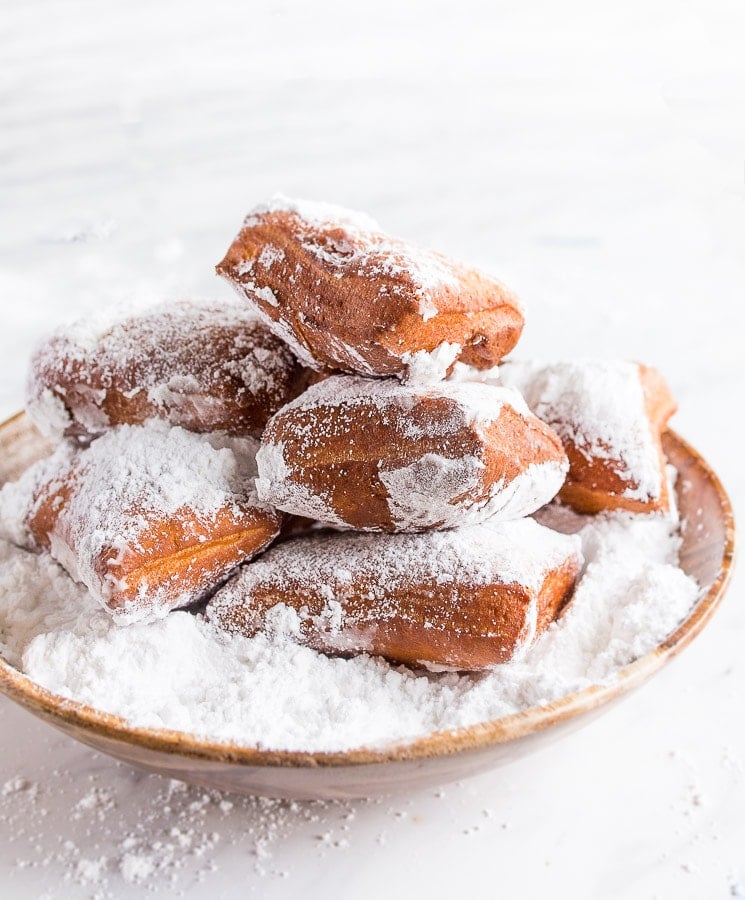 Homemade beignets from scratch in bowl with powdered sugar.