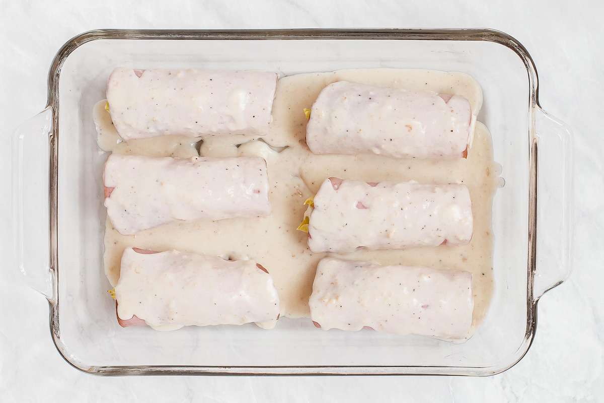 Endives wrapped in ham and covered with béchamel in baking dish.