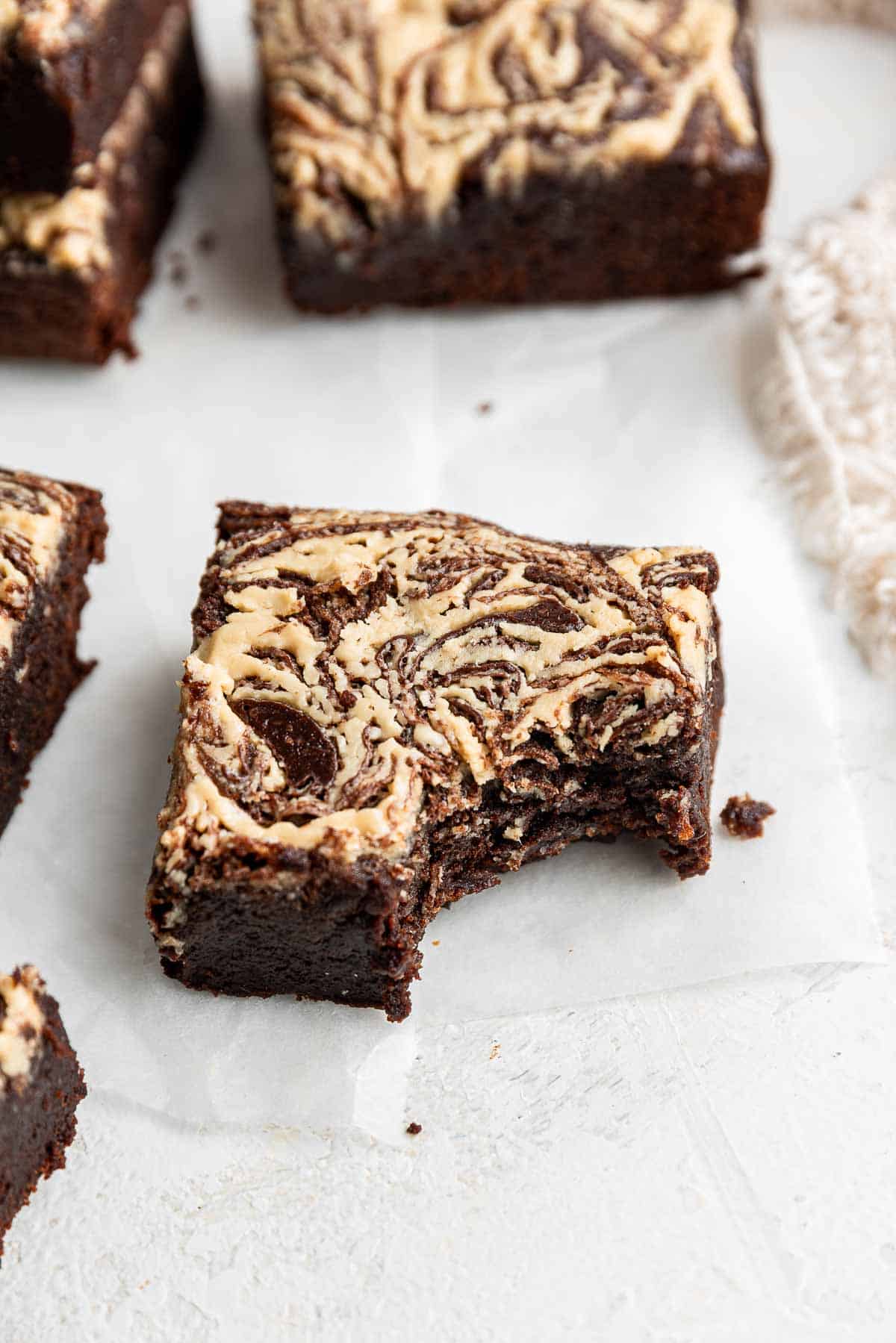 Tahini brownie with bite missing on white parchment paper.