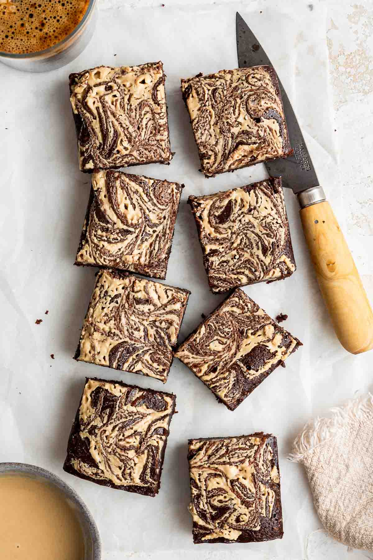 Overhead shot of tahini brownies cut into eight small squares with chunky knife.
