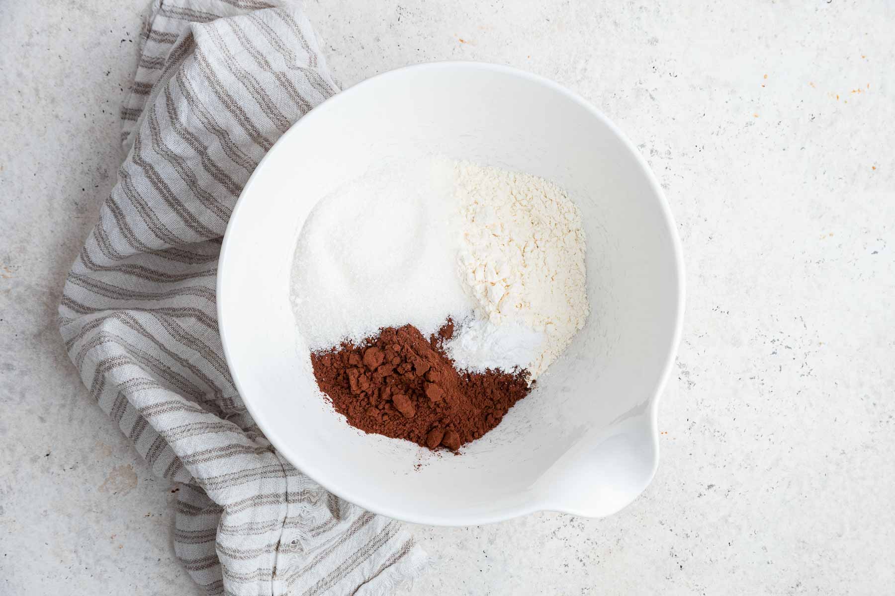 White bowl with flour, cocoa powder, baking powder and salt.