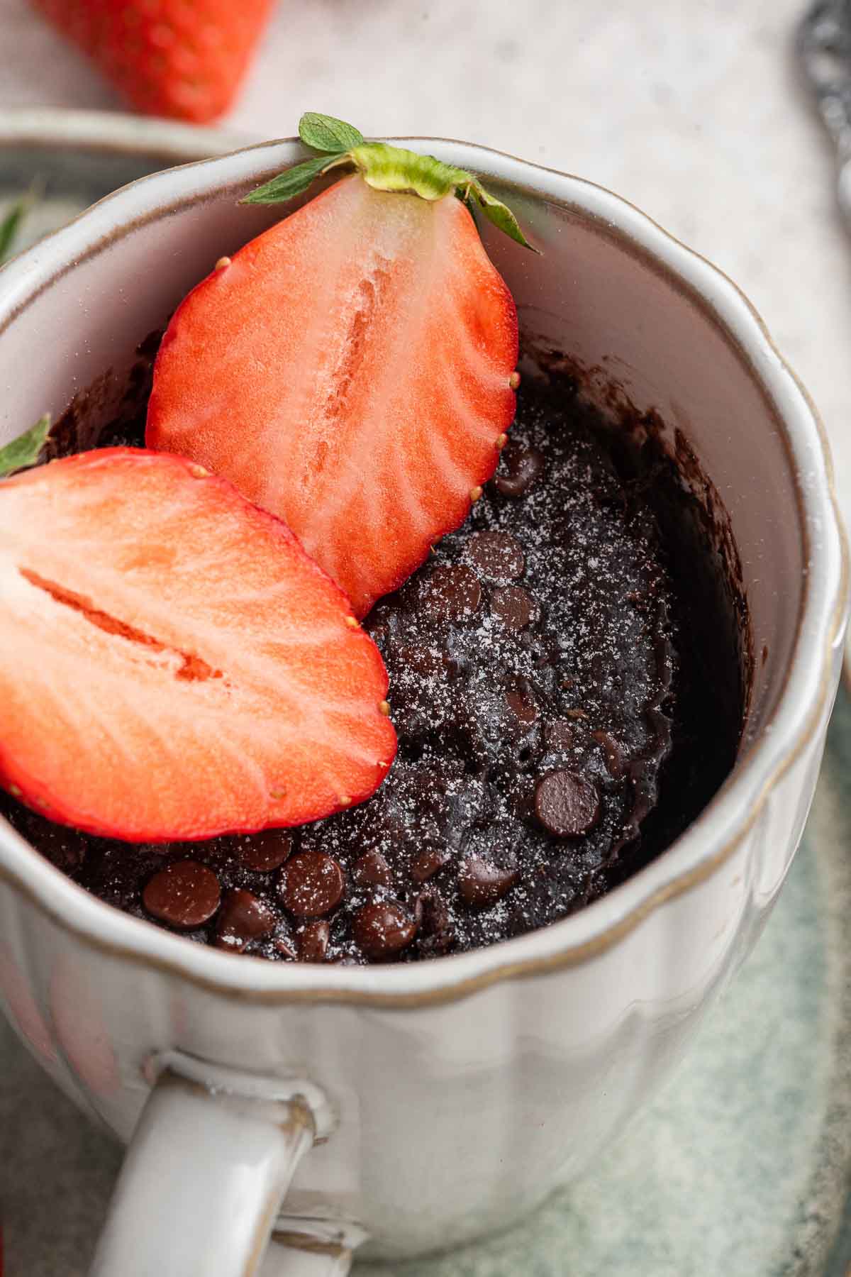 Chocolate mug cake with fresh strawberries on top.
