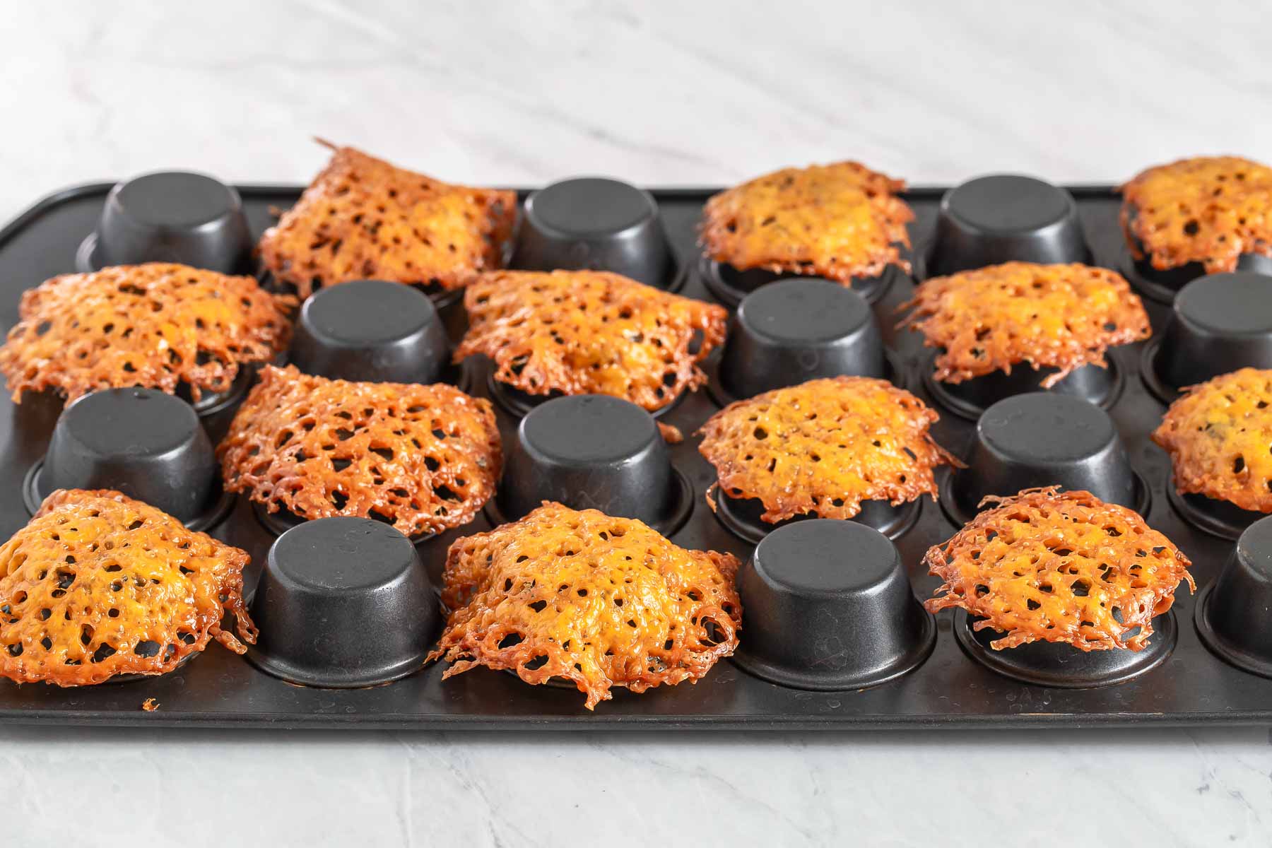 Cheddar cheese cups formed over mini muffin pan.
