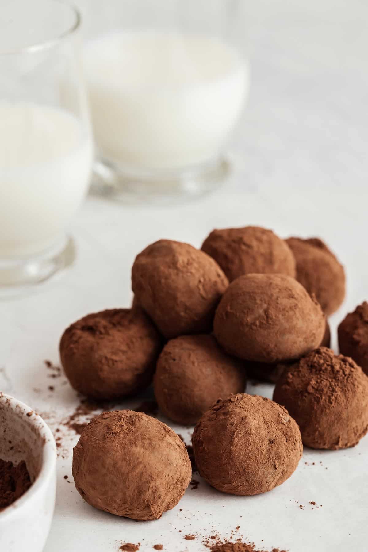 Pile of healthy chocolate truffles next to two glasses of milk.