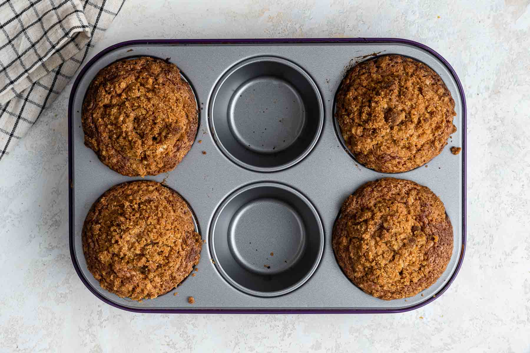 Four domed coffee cake muffins in a pan with only 6 holes.